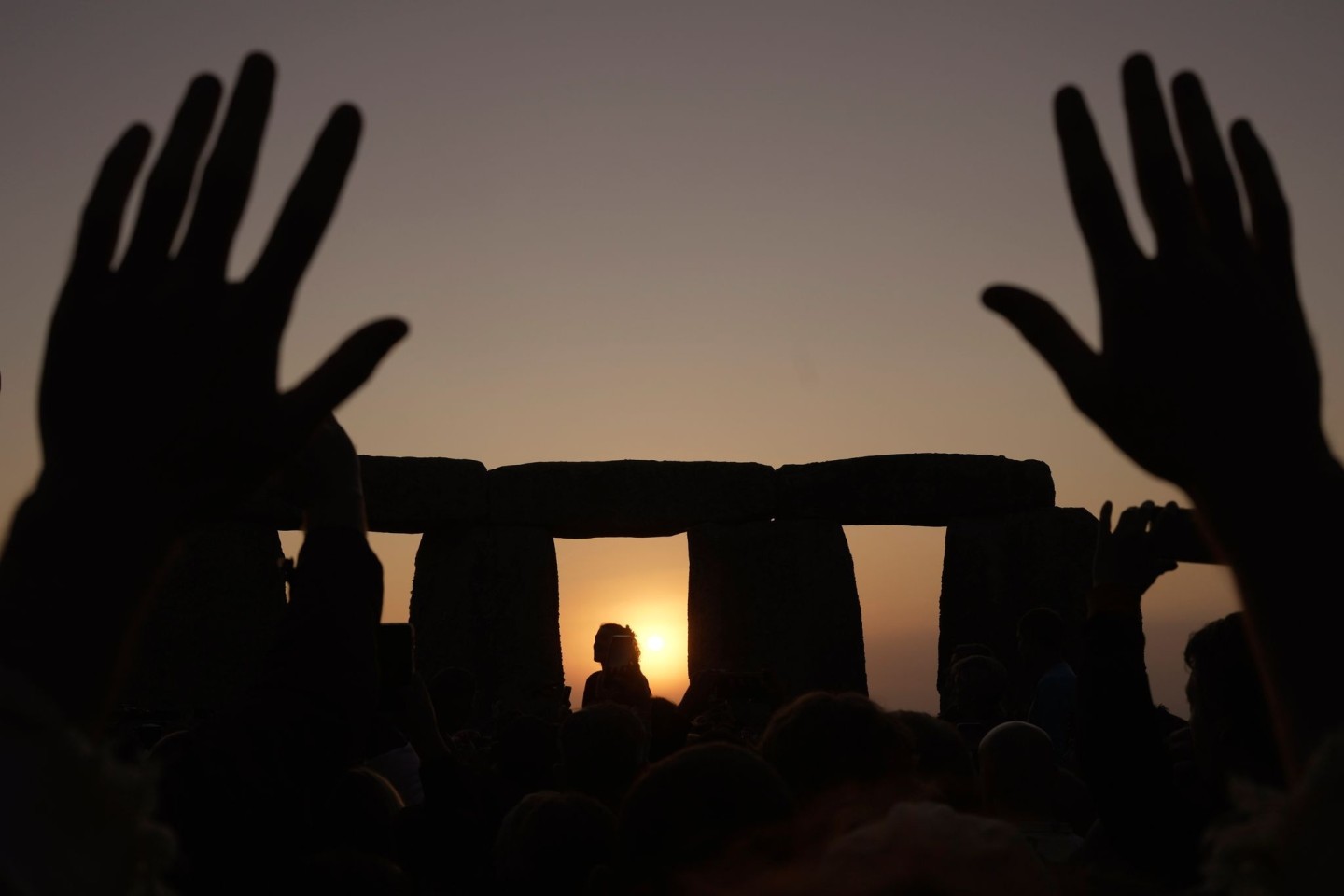 Menschen versammeln sich bei Sonnenaufgang am Tag der Sommersonnenwende um den Heel Stone in Stonehenge.
